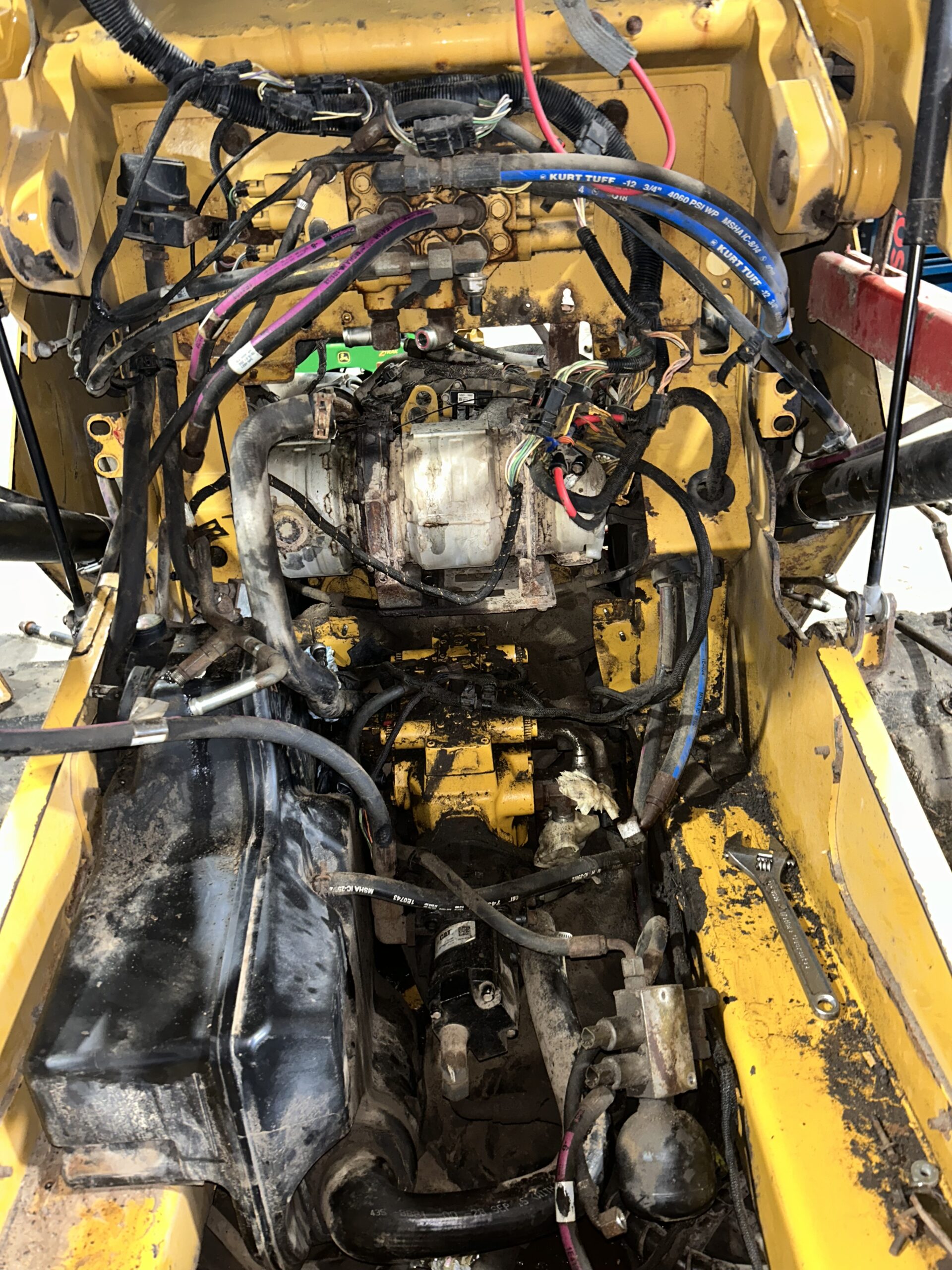 Exposed engine bay of heavy machinery showcasing various electrical wires, components, and signs of wear, highlighting maintenance needs.