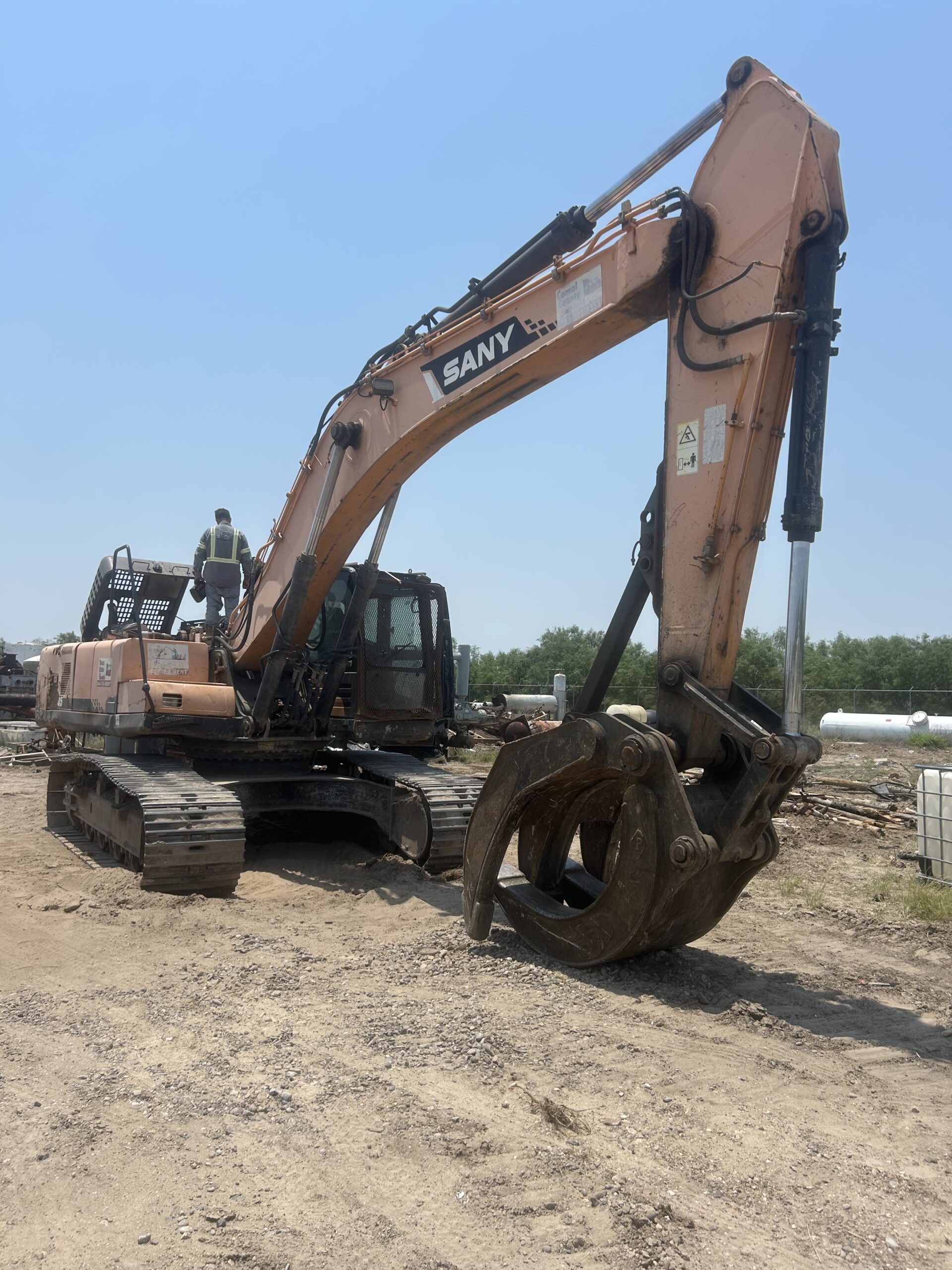 A SANY excavator with a claw attachment stands on a construction site, showcasing its heavy-duty capabilities for demolition or material handling.